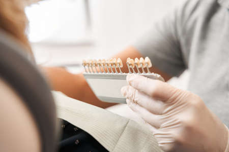 Dentist matching teeth color of senior womanの写真素材