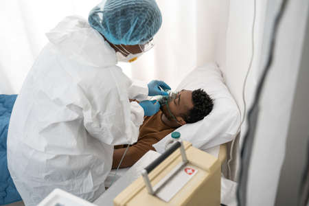 Man laying at the hospital bed and breathing through oxygen mask