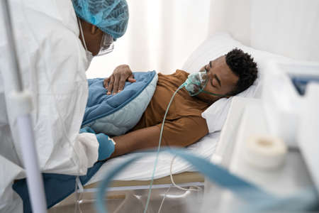 Doctor giving oxygen mask to the multiracial patient with covid-19