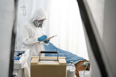 Doctor or nurse wearing protective suit examining the infected patient