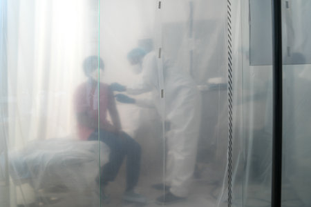 Doctor doing covid 19 vaccine to his female patient at the isolation unitの写真素材