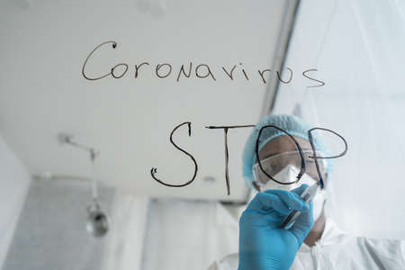 Doctor standing at medical clinic and writing at the transparent glass