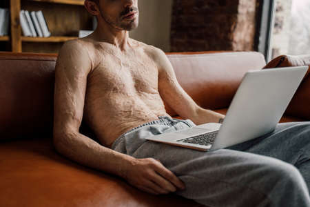 Man using laptop at home and looking at the screen, while chatting
