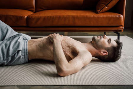 Man with a large scar after burn on the body laying at the floor and relaxingの写真素材