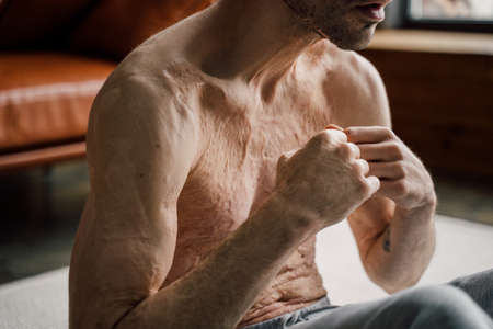 Caucasian man doing press on a mat at home while tense his musclesの写真素材