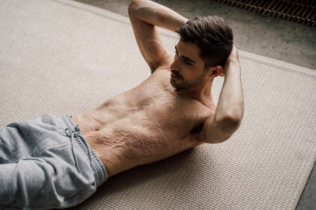 Man with scars at the skin after burn practicing abdominal crunches, rock press exercise