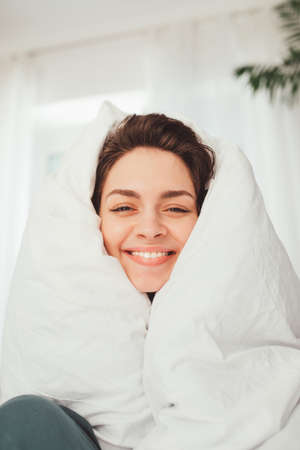 Woman feeling happiness while spending weekend at home wrapped at blanketの写真素材