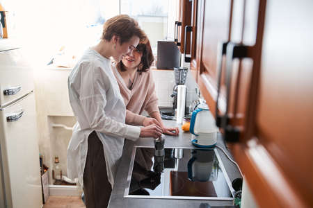 Beautiful young couple preparing coffee while standing in the kitchen at home