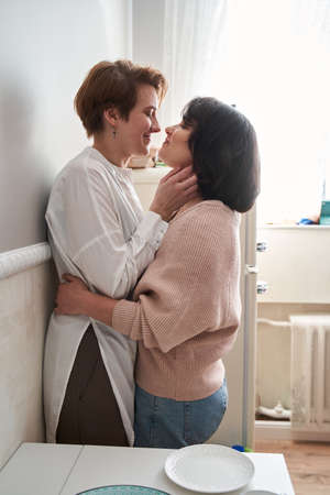 Loving joyful young couple embracing while cooking together in the kitchenの写真素材