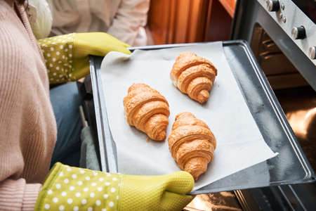 Caucasian woman is baking croissants with her lovely girlfriendの写真素材