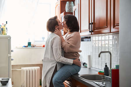 retty woman sitting at the table and hugging her girlfriendの写真素材