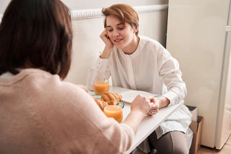 Lesbian couple talking during breakfast while sitting at the kitchenの写真素材