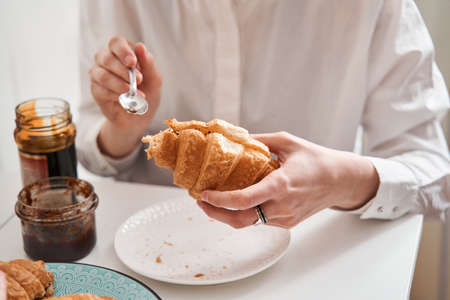 Woman putting jam at the croissant while having breakfast with her girlfriendの写真素材