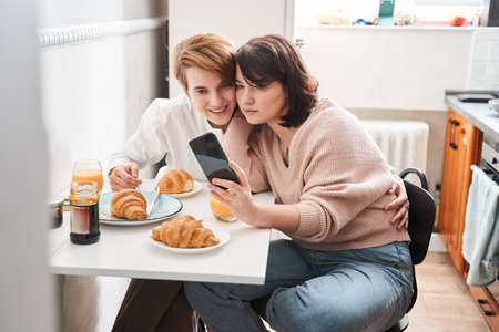 Lesbian couple holding smartphone and posing while making selfie togetherの写真素材