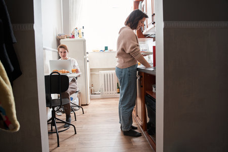 Girl cleaning plates after breakfast while spending time with her girlfriendの写真素材