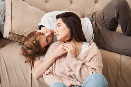 Couple relaxing on a couch at home while enjoying spending time togetherの写真素材