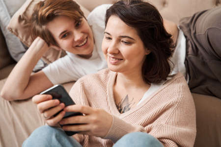 Woman holding her smartphone while showing something to her girlfriendの写真素材