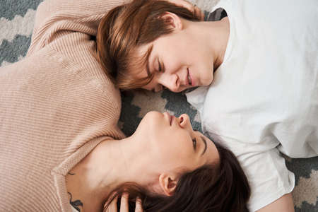 Lesbian couple laying at floor while spending romantic weekend with each otherの写真素材