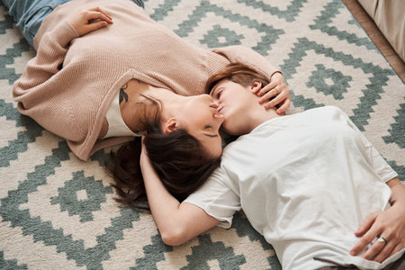 Lesbian woman turning head to her girlfriend while kissing her at the chickの写真素材