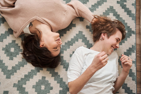 Pleasant young loving couple laying at the floor and laughing out loudの写真素材