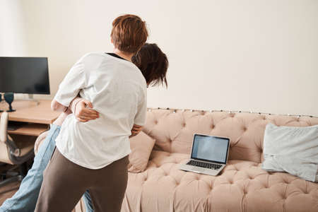 Adorable lesbian girl looking at the laptop screen while dancingの写真素材