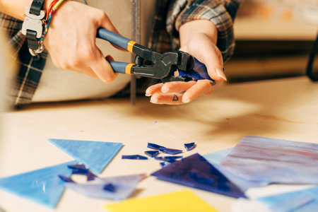 Female artist cutting sheets of stained glass into small mosaic squaresの写真素材