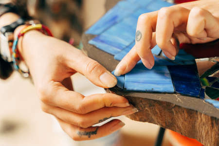 Young girl sitting and holding a tweezers, while making a mosaicの写真素材