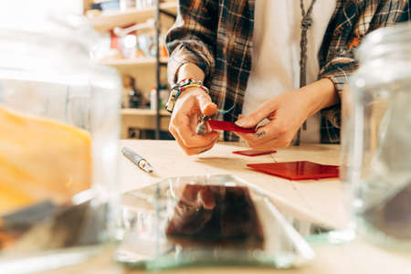 Woman artist holding red glass and cutting it with special tools while workingの写真素材