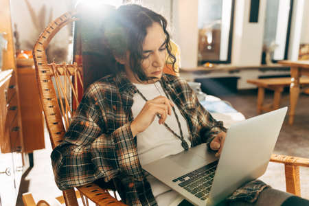 Lady working or studying at the armchair at her cozy flat