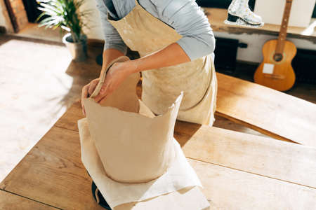 Happy potter making a ceramic pot on the pottery table