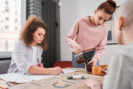 Girls making handmade posters about feminism together at the officeの写真素材