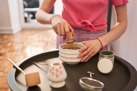 Female with pink hair making vegan matcha cappuccino with oat milk