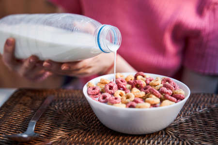 Woman sitting at the kitchen and holding bottle of milk