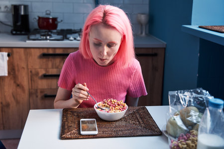 Woman sitting at the kitchen and having her breakfast of corn flakes