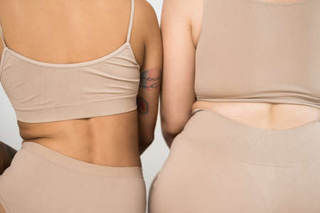 Strong girl with tattoo sitting near to plus size girl with folds at her bodyの写真素材