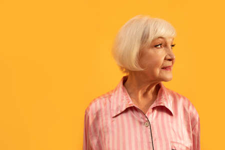 Woman with grey hair wearing striped shirt smiling positively and looking awayの写真素材