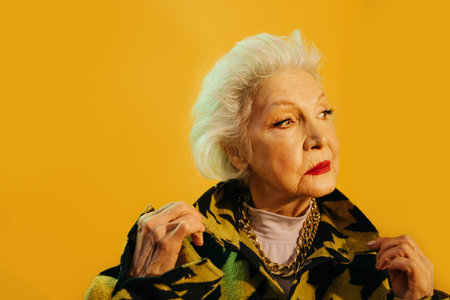 Woman wearing stylish coat adjusting her collar while standing at the studioの写真素材