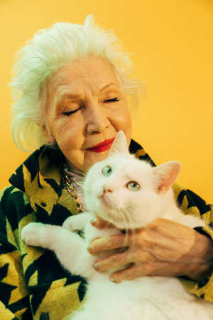 Female holding her white cat with different eyes while posing at the studioの写真素材