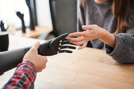 Man holding robotic hand while discussing it with his female client or colleagueの写真素材