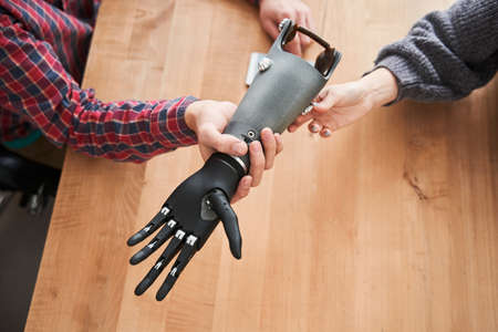 Male engineer showing a prosthesis of a hand to his female colleague