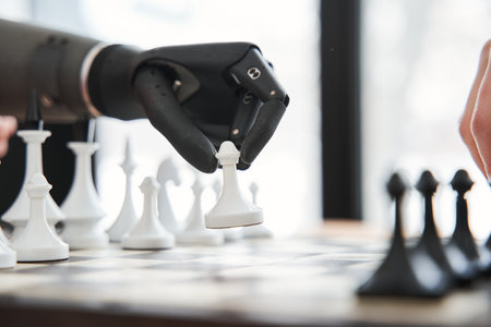Engineer making move with black bionic hand while playing at the chessの写真素材