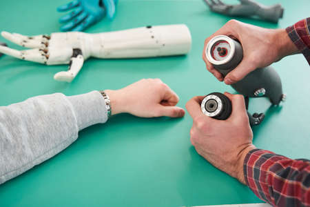 Two scientists examining mechanical hand in laboratoryの写真素材