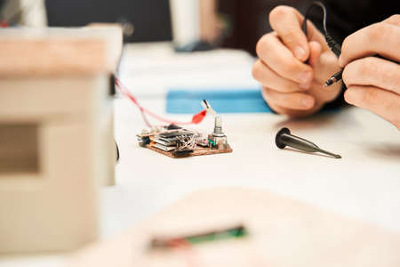 Male engineer sitting at the table and working with circuits and boards