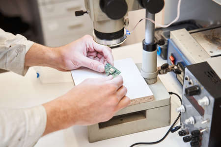 Engineer wearing white robe looking at the microscope at the schemaの写真素材