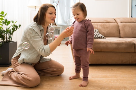 Woman sitting at the floor and showing soap bubbles to her daughter