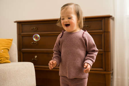 Girl with down syndrome looking at the soap bubble while feeling great emotions