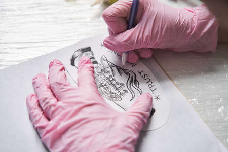 Woman wearing protective gloves carries over the drawing to the transferの写真素材
