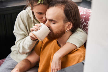 Woman feeding her husband with hot beverage at the balcony at home