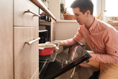 Man using special fabric for get out hot form while preparing ratatouille