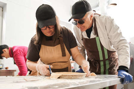 Chef preparing a pie with his female assistant at the industrial kitchen